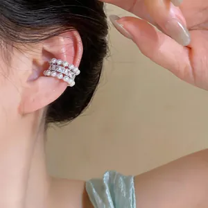 Close-up of elegant three-row ear cuff with pearls and square zircons worn by a model