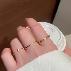 Primo piano di tre anelli dorati sottili con zirconi indossati su una mano stile vintage.