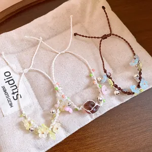 Vue détaillée des bracelets faits main avec fleurs en résine et clochettes sur lin.