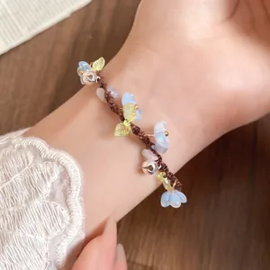 Gros plan d'un bracelet artisanal avec fleurs en résine bleues et petites clochettes