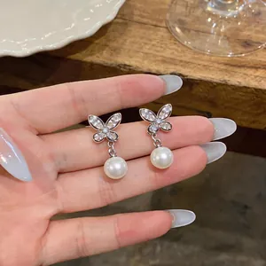 Close-up detail view of butterfly earrings with sparkling zirconia wings and elegant pearl drops