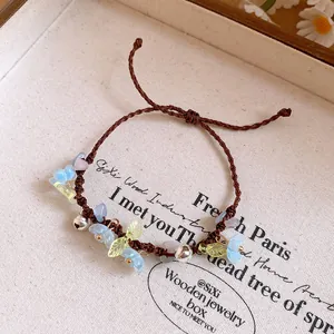 Détail d'un bracelet tissé avec fleurs en résine bleue et petits grelots argentés