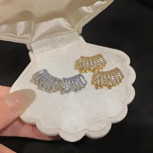 Dettaglio orecchini a C placcati oro 14K con zirconi brillanti in una scatola a conchiglia