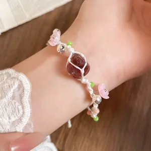 Vue détaillée d'un bracelet tissé à la main avec fleurs en résine rose et pierre rouge.