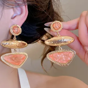 Detail of vintage geometric orange triangle drop earrings with hammered gold finish