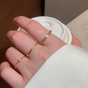 Dettaglio di tre anelli d'oro in stile vintage con zirconi scintillanti sulle dita.