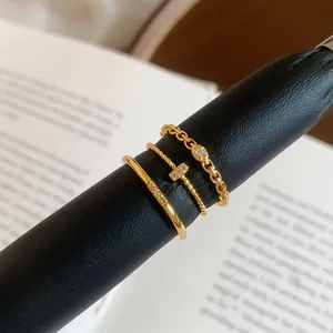 Primo piano di tre anelli dorati stile vintage con zirconi brillanti su supporto.