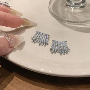 Primo piano di eleganti orecchini a ventaglio con zirconi scintillanti su piatto bianco