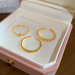 Vista dettagliata di tre eleganti anelli vintage in oro con zirconi in una scatola rosa