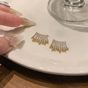 Dettaglio macro di orecchini placcati in oro 14K con zirconi scintillanti a ventaglio multistrato
