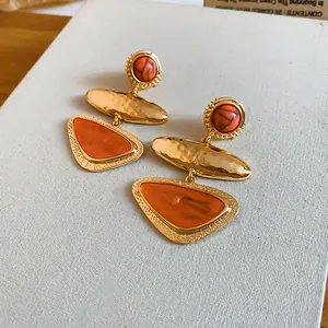 Detailed macro shot of vintage geometric triangle earrings with orange stones and gold finish
