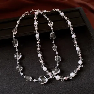 Close-up detail of elegant beaded necklace featuring clear crystal stones and white pearls.