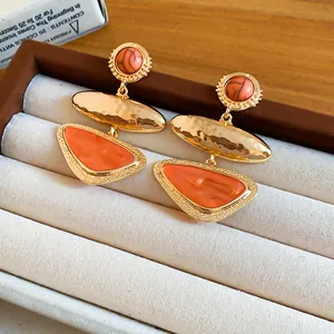 Detail view of vintage geometric triangle earrings with orange resin and hammered gold finish