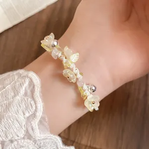 Détail d'un bracelet de fleurs en résine fait main avec clochettes et pendentifs