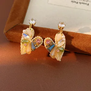 Detaillierte Makroansicht eleganter herzförmiger Ohrringe mit bunten Kristallen und Perlen.