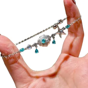 Elegant silver bracelet with blue teardrop zircon, starfish and seashell charms.