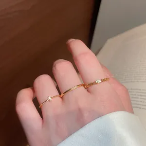 Dettaglio di anelli vintage dorati con zirconi scintillanti sulle dita e sfondo di un libro