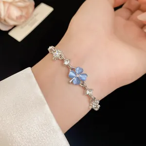 Detailed view of silver-tone bracelet featuring blue cat's eye four-leaf clover