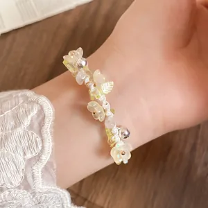 Détail d'un bracelet en fleurs de résine et grelots sur poignet avec de la dentelle