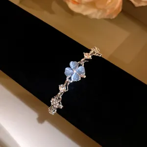 Detailed macro view of a silver bracelet featuring a blue cat's eye clover and zircons.