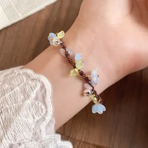 Gros plan détaillé d'un bracelet tissé à la main avec fleurs en résine et petites cloches