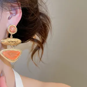 Detailed close-up showing vintage orange geometric triangle dangling earrings on a model