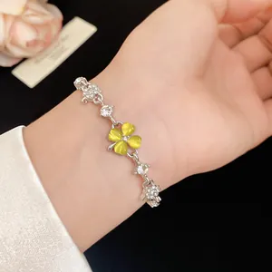 Close-up of a silver-tone bracelet with yellow cat's eye four-leaf clover and zircons.