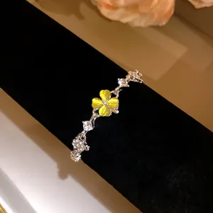 Macro view of silver bracelet featuring a glowing yellow cat's eye four-leaf clover