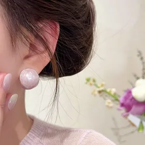 Detailed view of elegant pale pink oval stud earrings worn by a model in soft lighting