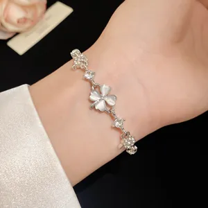 Detailed macro shot of a silver four-leaf clover bracelet with cat's eye stones on wrist