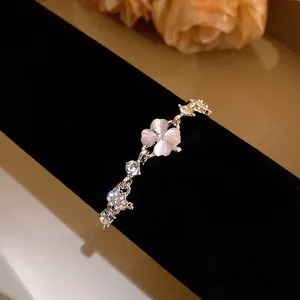 Detail view of a four-leaf clover bracelet with pink cat's eye stone and zircons