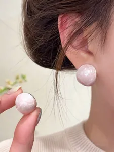 Detailed close-up of pink oval stud earrings with pearl-like drip oil finish