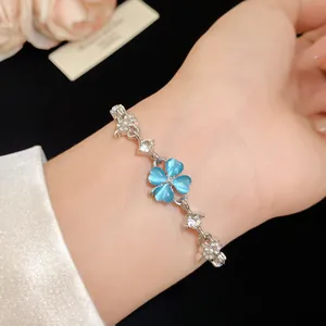 Close-up of an elegant blue cat-eye stone four-leaf clover bracelet on a feminine wrist