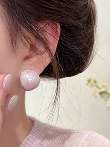 Close-up detail of a pale pink pearlescent oval stud earring worn by an Asian model