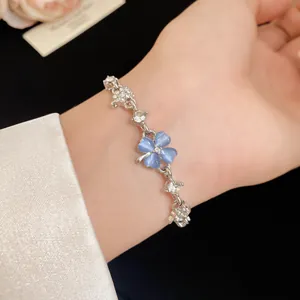 Detailed view of a delicate silver bracelet with blue cat-eye stone four-leaf clover.