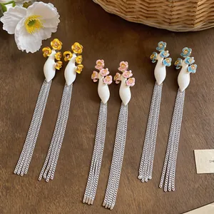 Detail view of long tassel earrings with colorful enamel flowers in three pastel shades