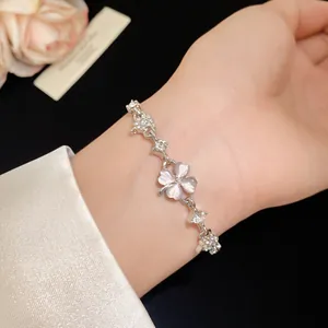 Elegant close-up of cat's eye stone clover bracelet with zircons worn on a wrist.