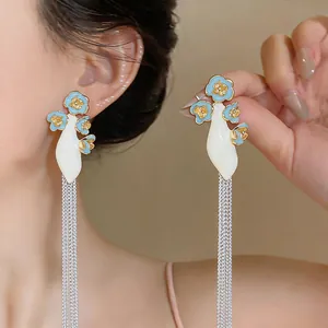 Detail shot of long tassel earrings with blue enamel flowers and silver chains