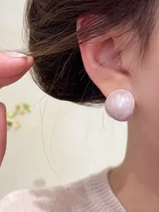 Detailed macro shot of elegant light pink oval drip oil stud earrings worn on ear