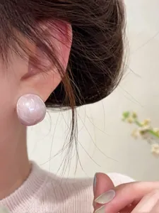 Detailed macro view of pale pink oval stud earrings showing glossy texture and elegant fit