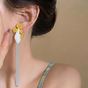 Close-up of elegant long tassel earrings with yellow enamel flowers on an Asian model