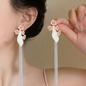 Detailed view of elegant pink flower earrings with long silver tassel chains on model