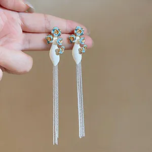 Close-up detail of elegant blue drip oil floral earrings with long silver tassel chains