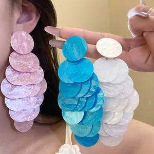 Close-up view of marbled acrylic circle tassel earrings in pink, blue, and white colors.