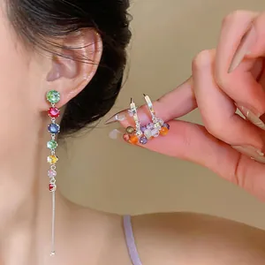 Close-up view of elegant silver pin zircon tassel earrings and colorful hoop drops