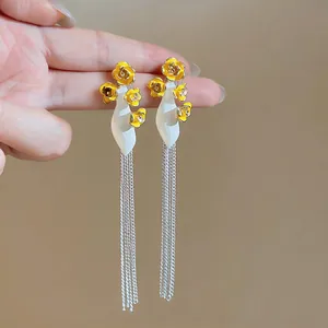 Detail view of elegant long tassel earrings featuring yellow flowers and silver-tone chains.
