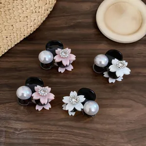 Detailed close-up of elegant small flower pearl hair claw clips with sparkling rhinestones