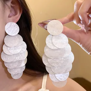 Detailed macro view of white marbled acrylic tiered round tassel earrings on model