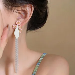 Macro detail of long silver tassel earrings featuring elegant pink enamel flowers