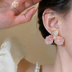 Detailed view of elegant French style pink flower stud earrings with pearl on ear
